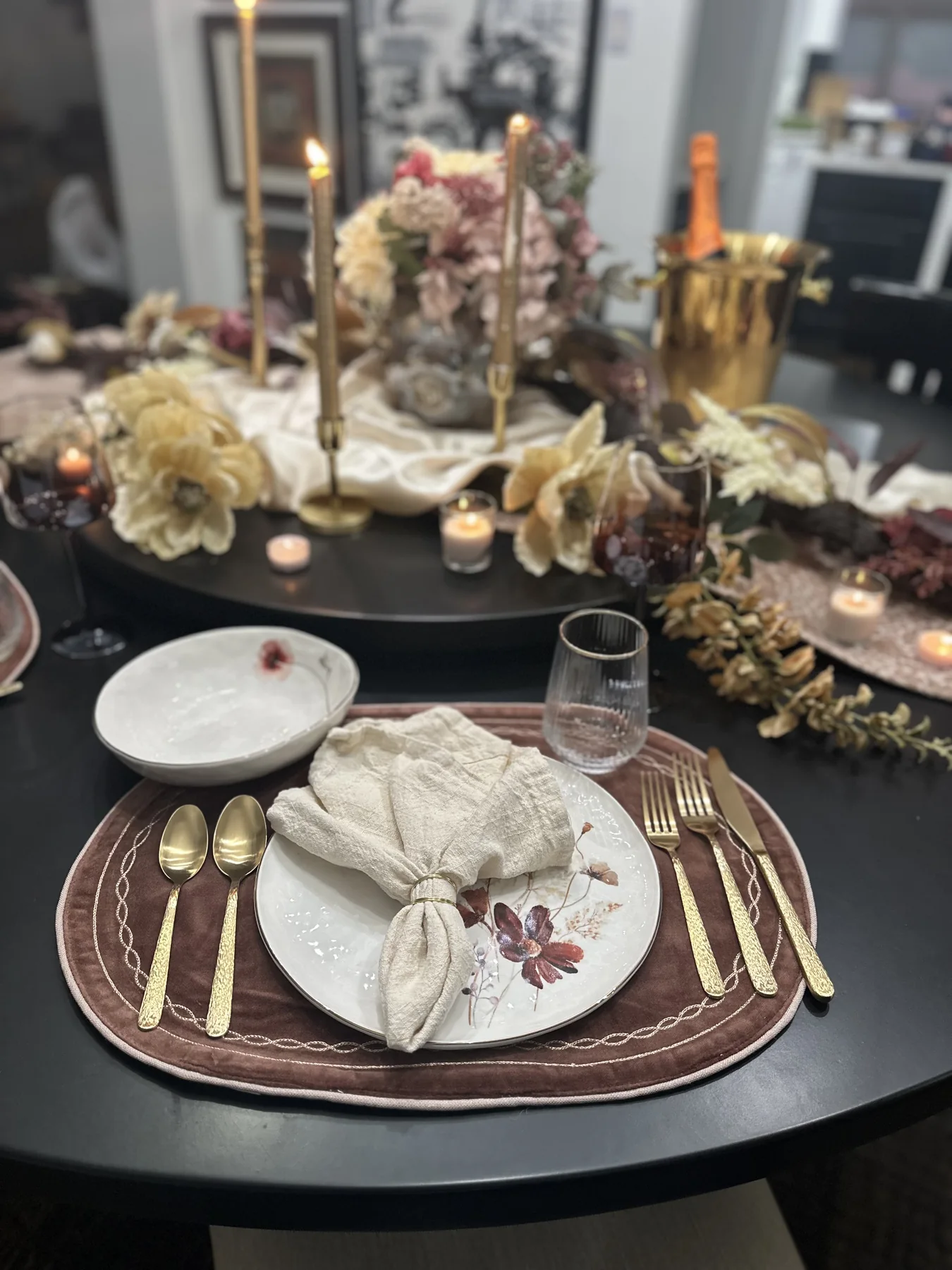 Elegant place setting with floral china, gold flatware, and candlelight
